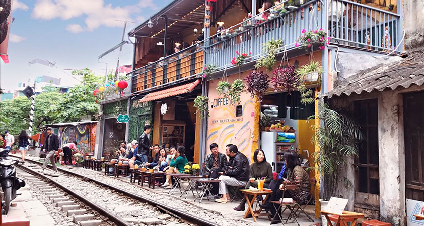 People enjoy coffee while waiting for the train coming across
